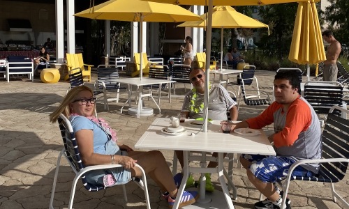 people sitting at a picnic table with an umbrella