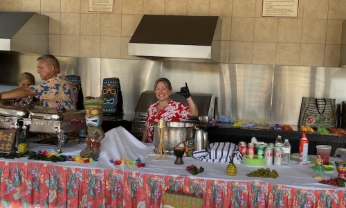 woman waving behind a table